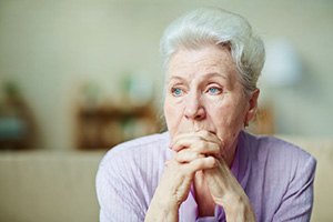 Sad senior woman sitting on sofa