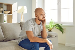 Man sitting on couch with a toothache