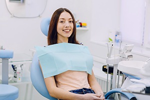 Female dental patient sitting in chair and smiling