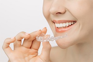 Woman holding Invisalign tray close to her mouth