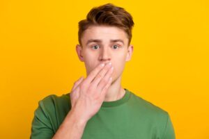 Concerned young man covering his mouth