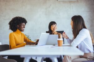 Three women conversing in office workspace 